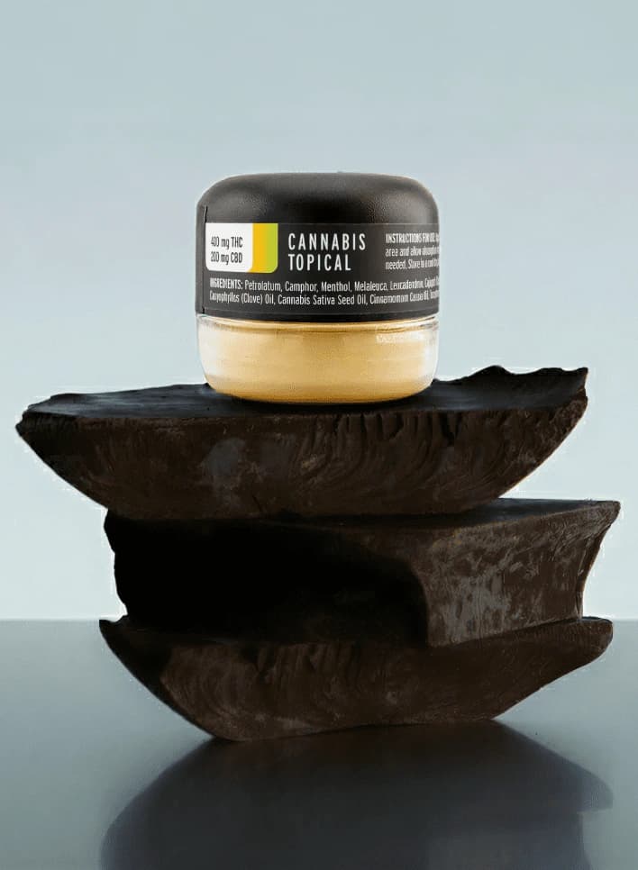 Jar of Dragonbalm cannabis topical resting on a stack of stones