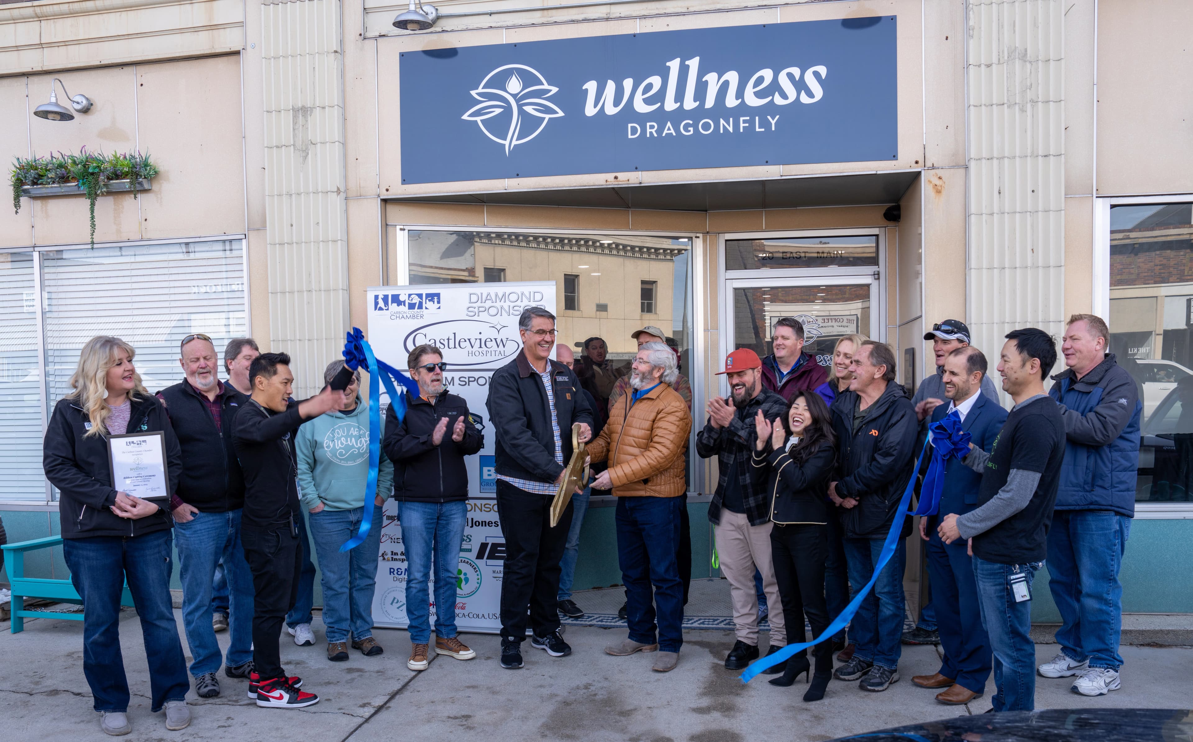 Cannabis pharmacy grand opening ribbon cutting with Dragonfly Wellness logo above